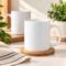 White ceramic mugs displayed on a wooden coaster in a warm, minimalist setting.