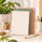 Cream spiral journal with gold binding, pastel-colored notebooks, and a pen on a minimalist desk.